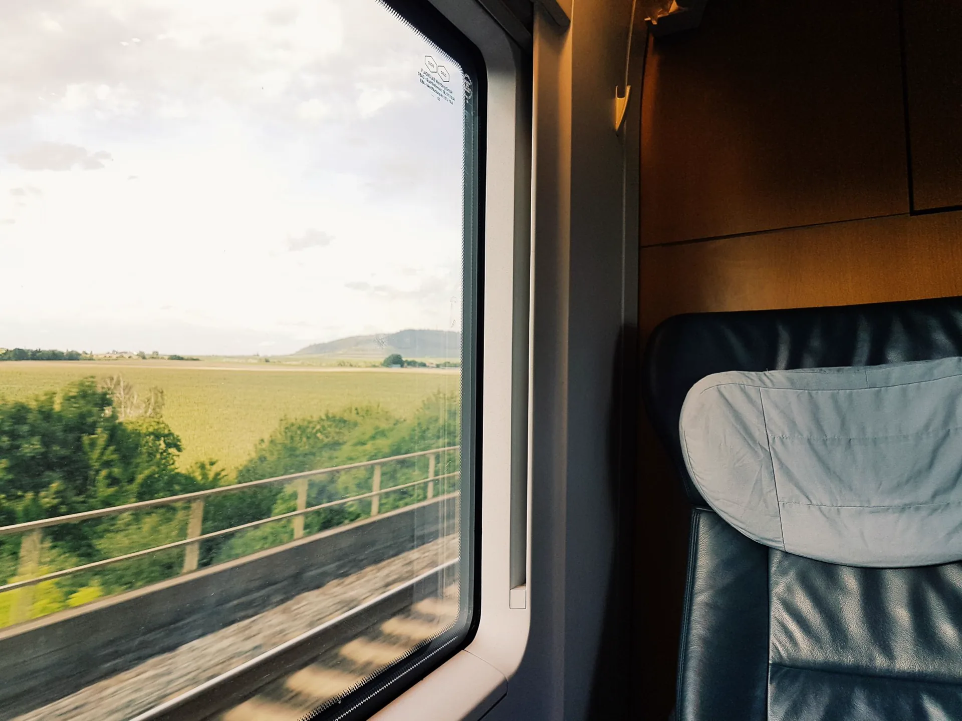 Vista dal finestrino di un treno su campi verdi e cielo azzurro